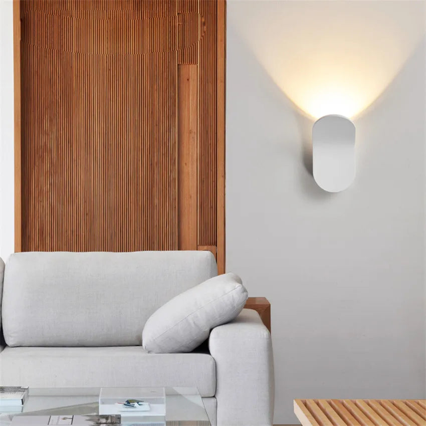 White Nordic Glow Wall Lamp lighting the wall beside a gray sofa