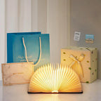 Storybook Folding Book Lamp glowing beside gift bags and wrapped presents