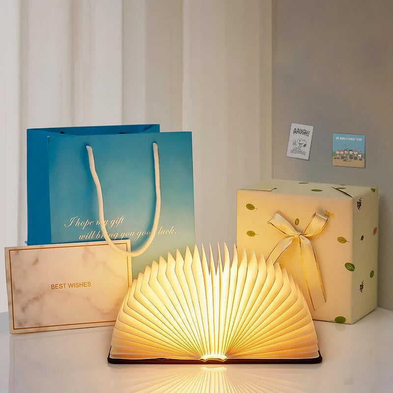 Storybook Folding Book Lamp glowing beside gift bags and wrapped presents
