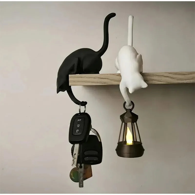 Black and white Gothic Cat Shelf Hook Figurines on a shelf holding keys and a small lantern