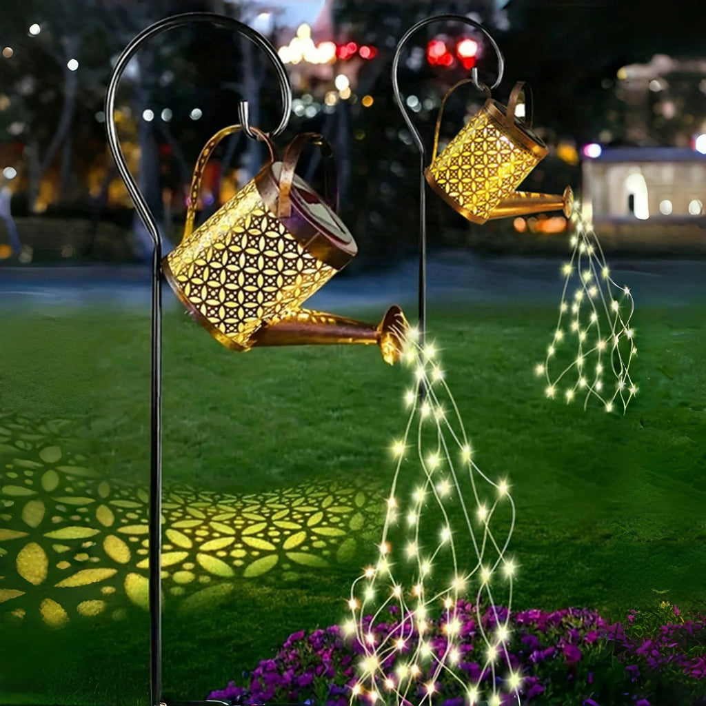 Solar Watering Can Garden Lantern pouring a stream of fairy lights onto a lawn at night